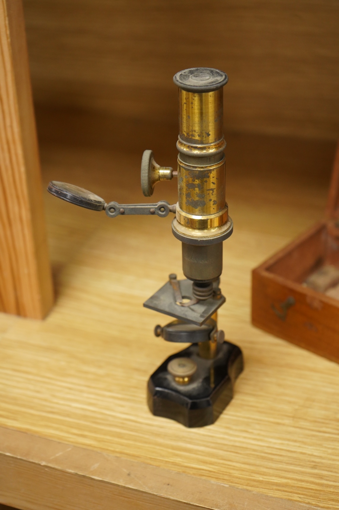 A late 19th/early 20th century French brass compound monocular microscope, height 20.5cms, together with a teak case; 23cm wide, 9cm deep, 7cm high